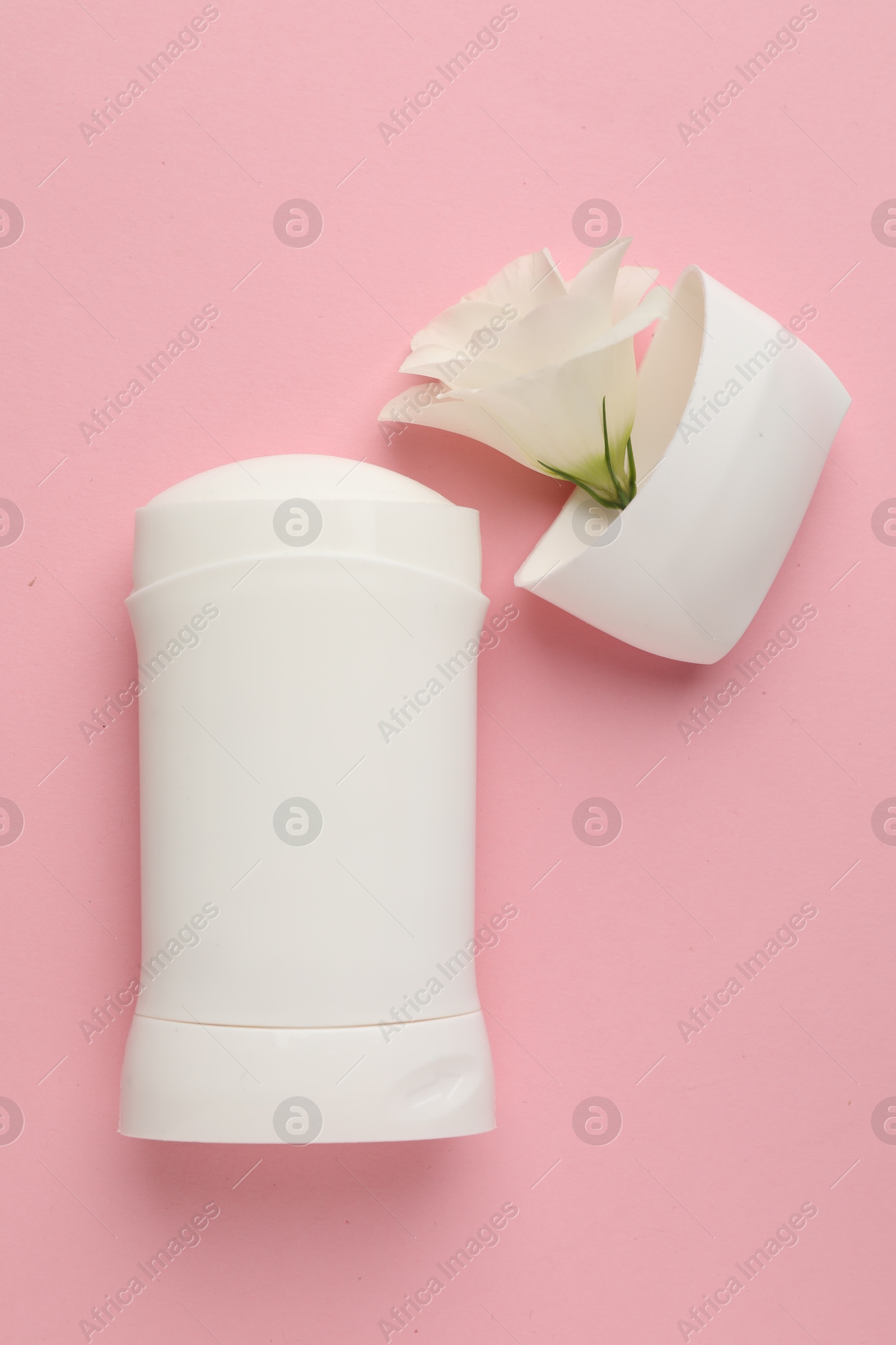 Photo of Solid deodorant and beautiful eustoma flower on pink background, top view