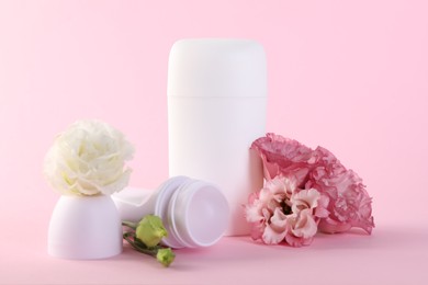 Photo of Different deodorants and beautiful eustoma flowers on pink background