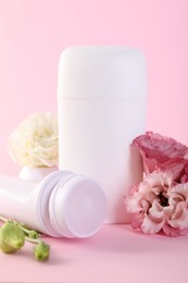 Photo of Different deodorants and beautiful eustoma flowers on pink background