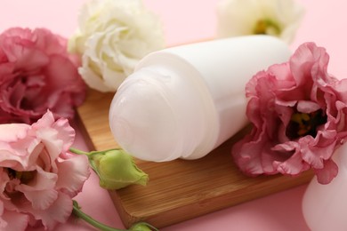 Roll-on deodorant and beautiful eustoma flowers on pink background, closeup