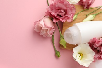 Photo of Roll-on deodorant and beautiful eustoma flowers on pink background, top view. Space for text