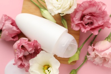 Photo of Roll-on deodorant and beautiful eustoma flowers on pink background, top view