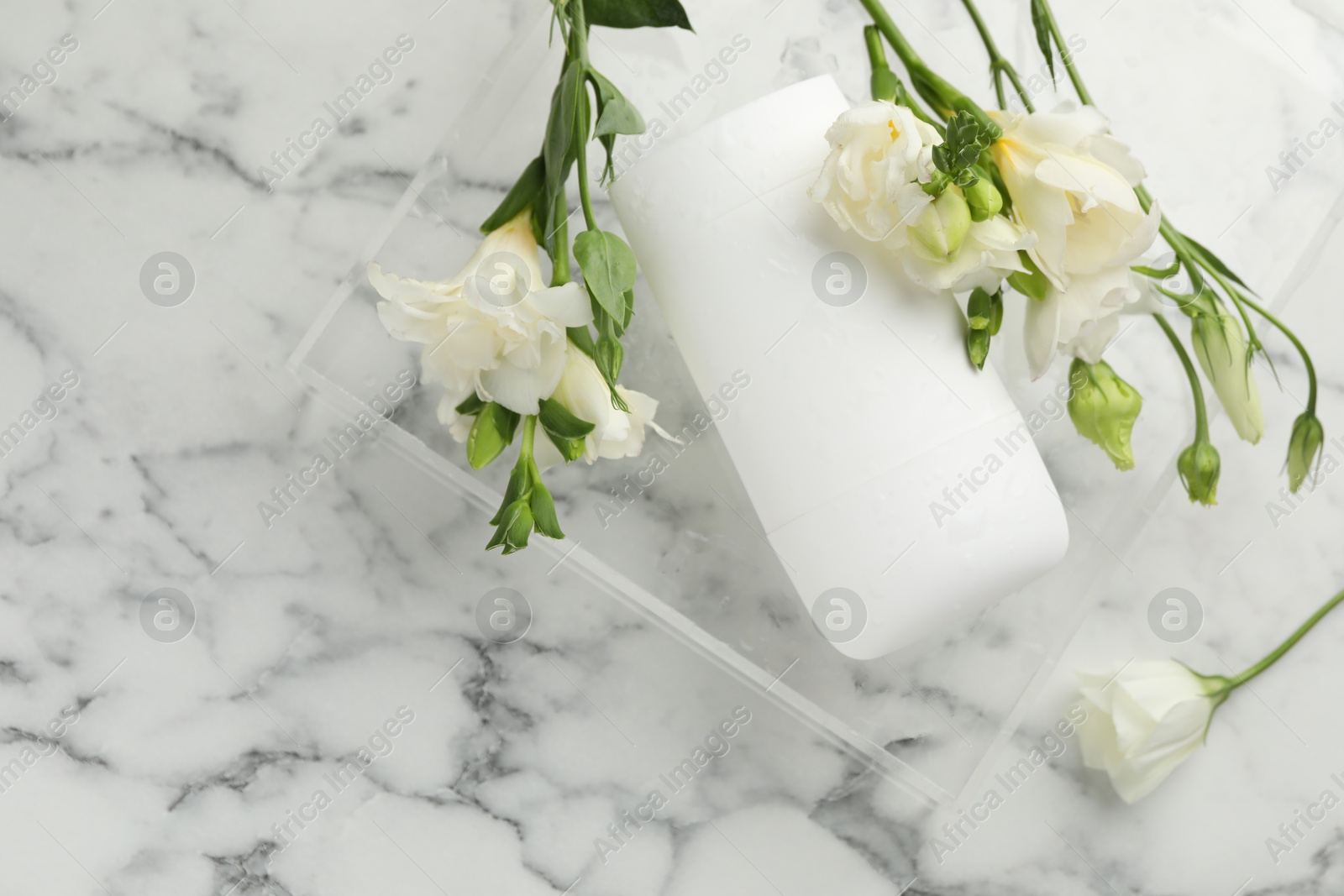 Photo of Solid deodorant and beautiful eustoma flowers on white marble table, top view