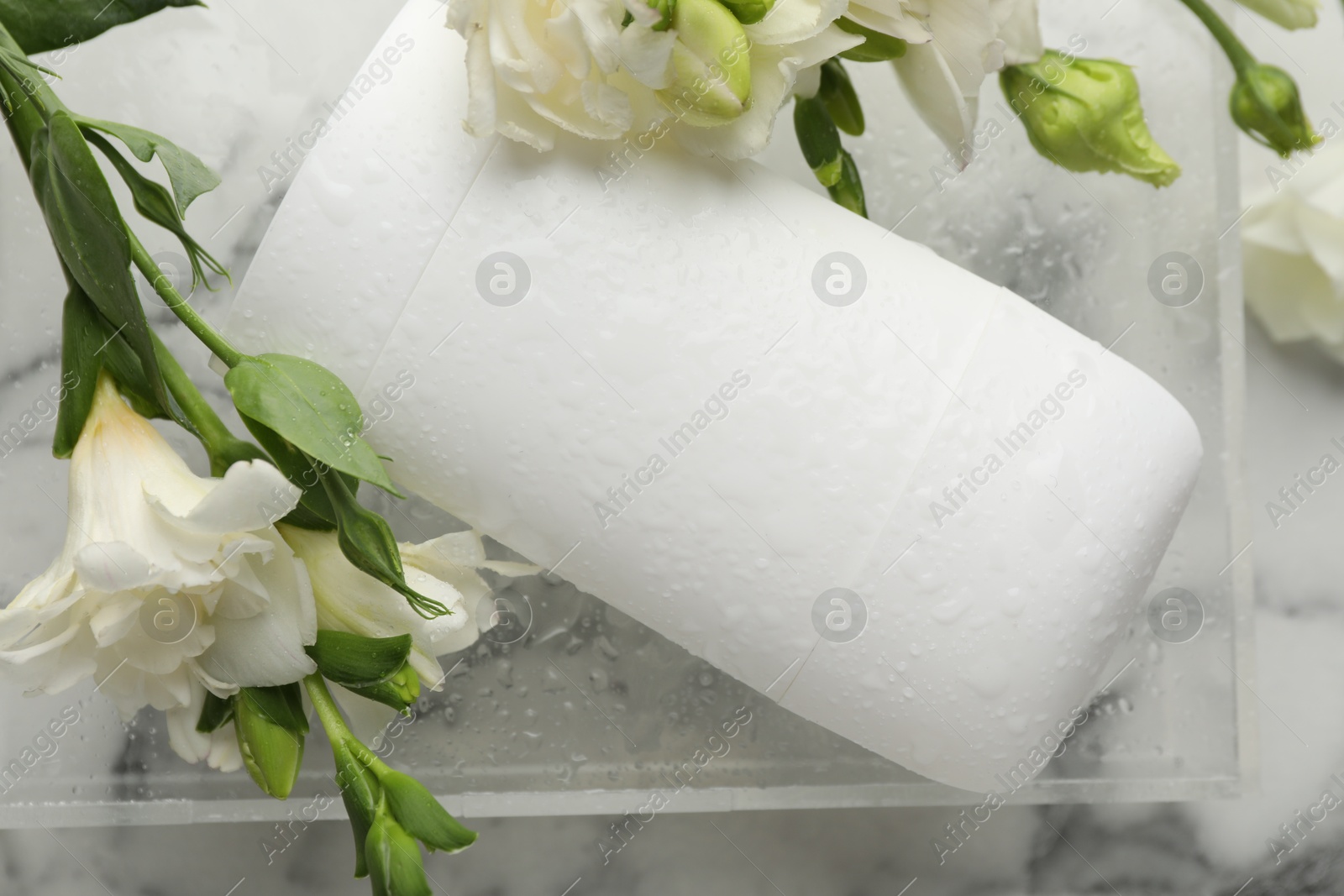 Photo of Solid deodorant and beautiful eustoma flowers on white marble table, top view