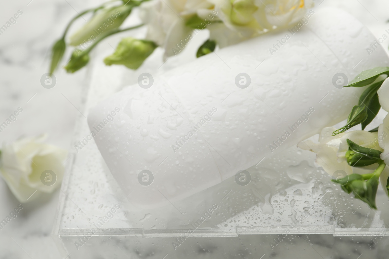 Photo of Solid deodorant and beautiful eustoma flowers on table, closeup