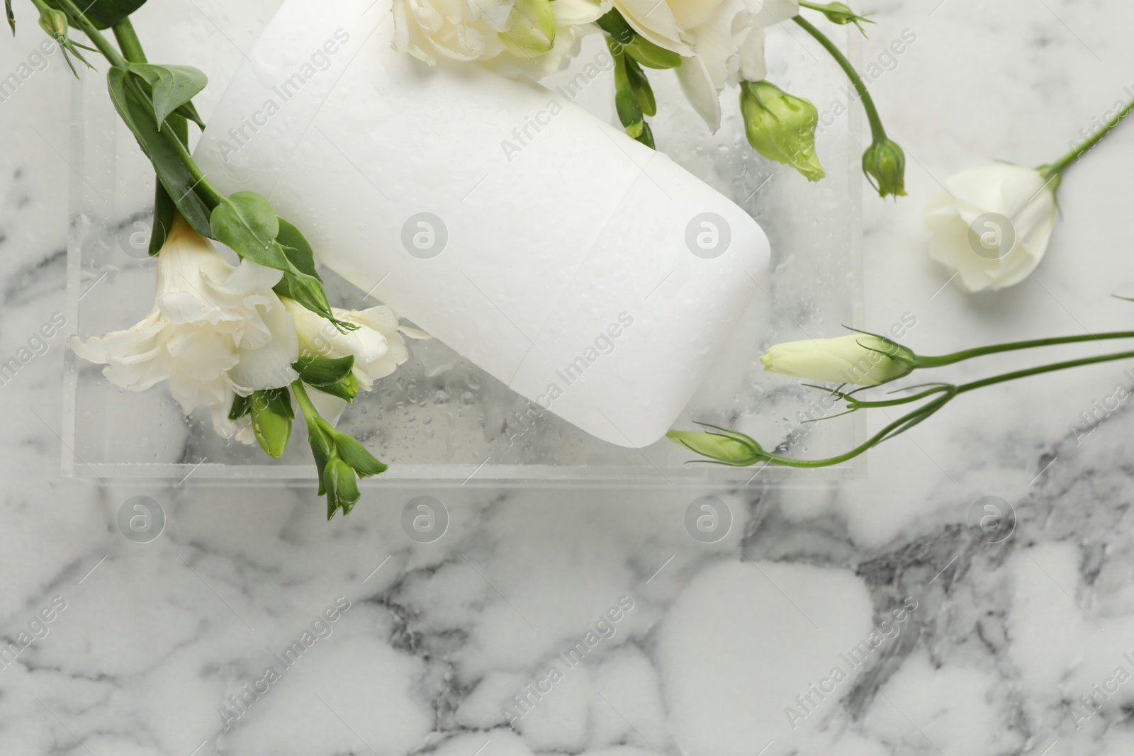 Photo of Solid deodorant and beautiful eustoma flowers on white marble table, top view