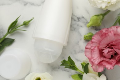 Photo of Roll-on deodorant and beautiful eustoma flowers on white marble table, flat lay