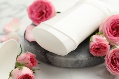 Photo of Solid deodorant and beautiful rose flowers on table, closeup