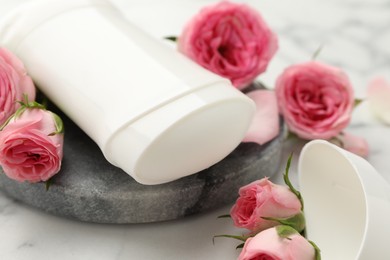 Photo of Solid deodorant and beautiful rose flowers on table, closeup