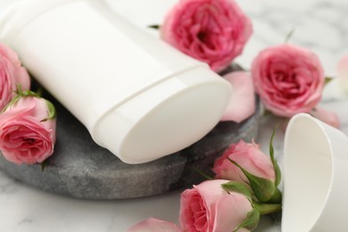 Photo of Solid deodorant and beautiful rose flowers on table, closeup