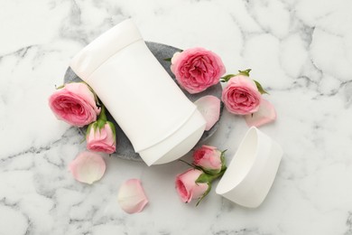 Photo of Solid deodorant and beautiful rose flowers on white marble table, flat lay