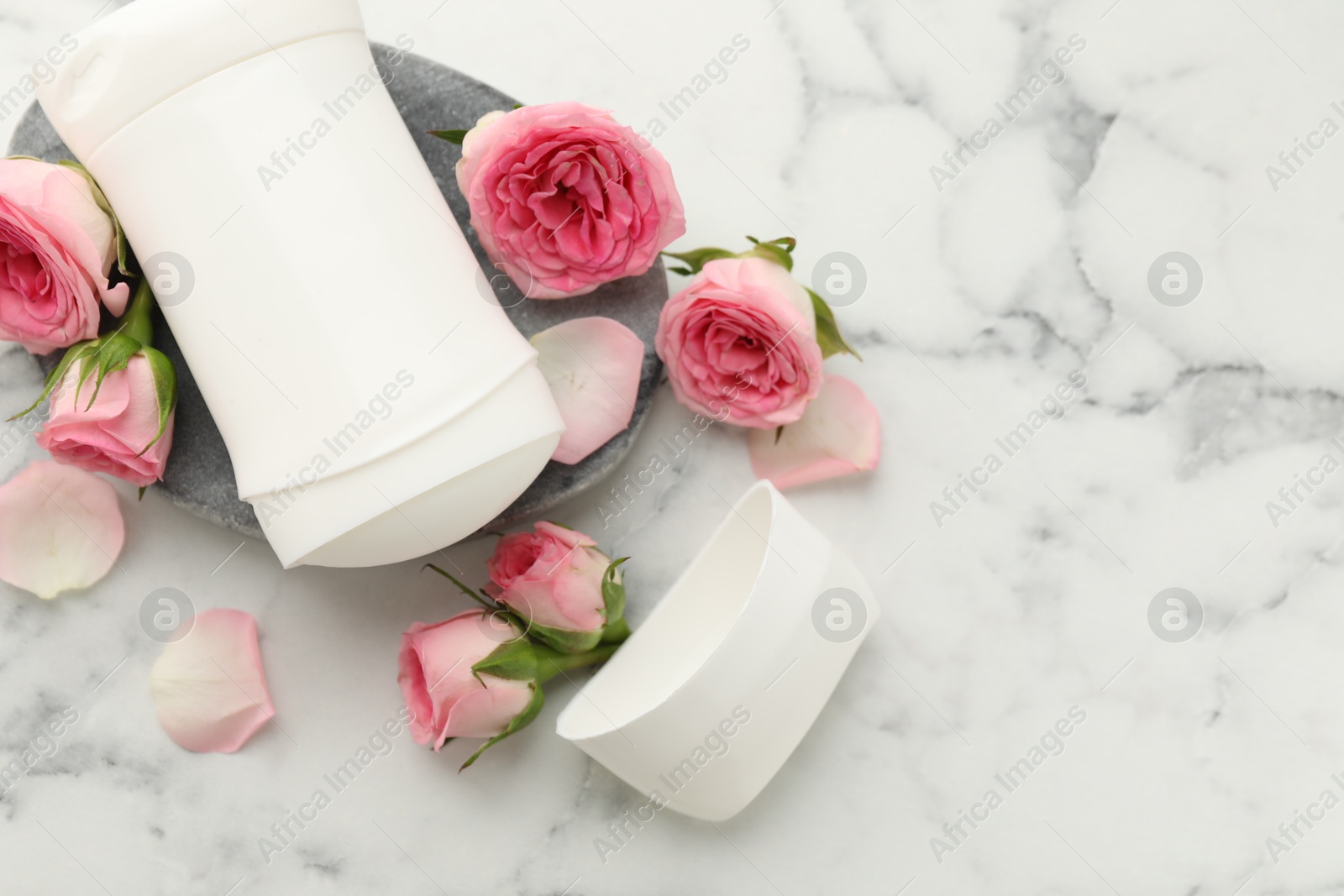 Photo of Solid deodorant and beautiful rose flowers on white marble table, flat lay. Space for text