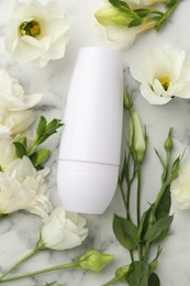 Photo of Roll-on deodorant and beautiful eustoma flowers on white marble table, flat lay