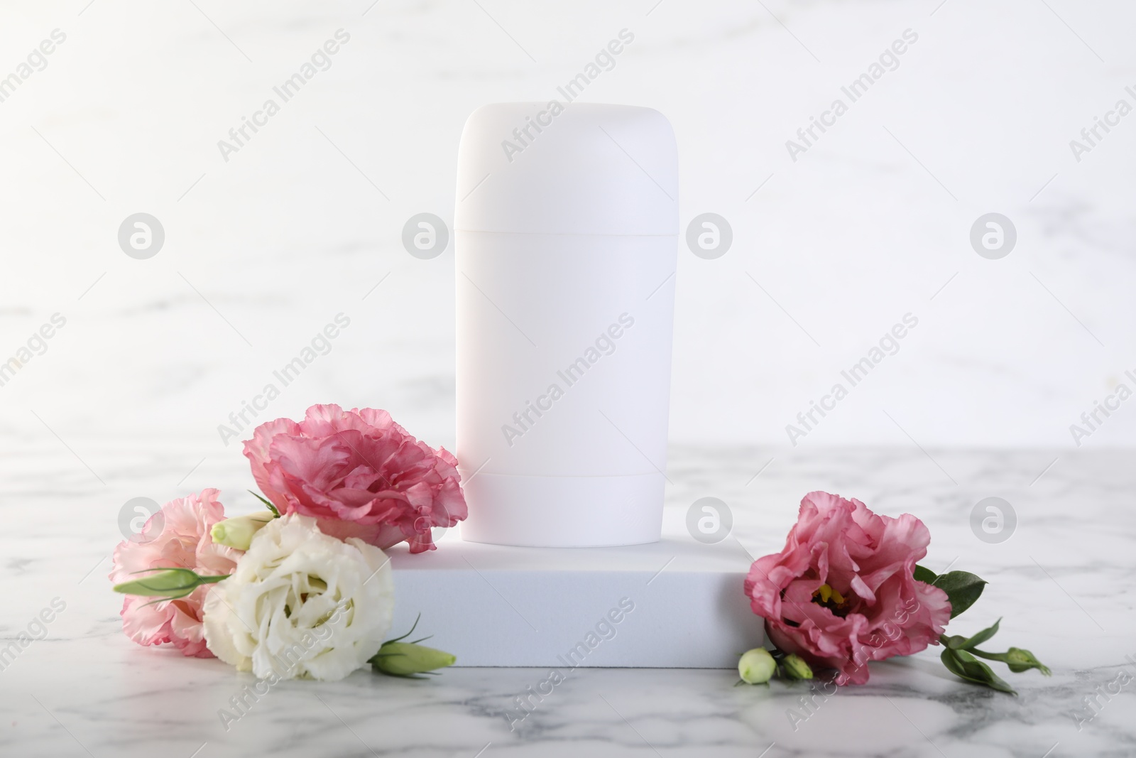 Photo of Solid deodorant and beautiful eustoma flowers on white marble table