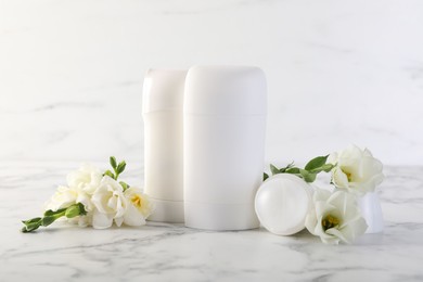 Photo of Solid deodorants and beautiful eustoma flowers on white marble table