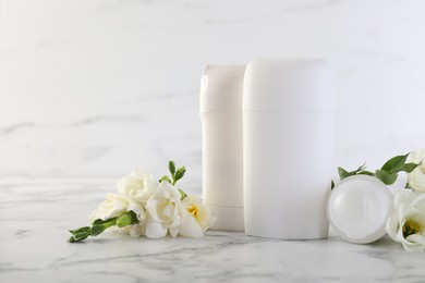 Photo of Solid deodorants and beautiful eustoma flowers on white marble table