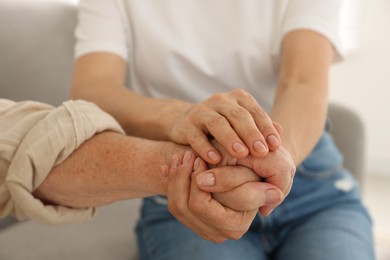 Photo of Caregiver supporting senior woman at home, closeup