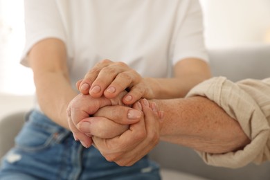 Caregiver supporting senior woman at home, closeup