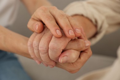 Photo of Caregiver supporting senior woman at home, closeup