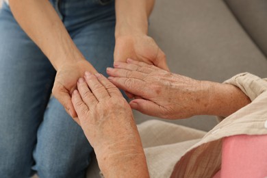 Photo of Caregiver supporting senior woman at home, closeup