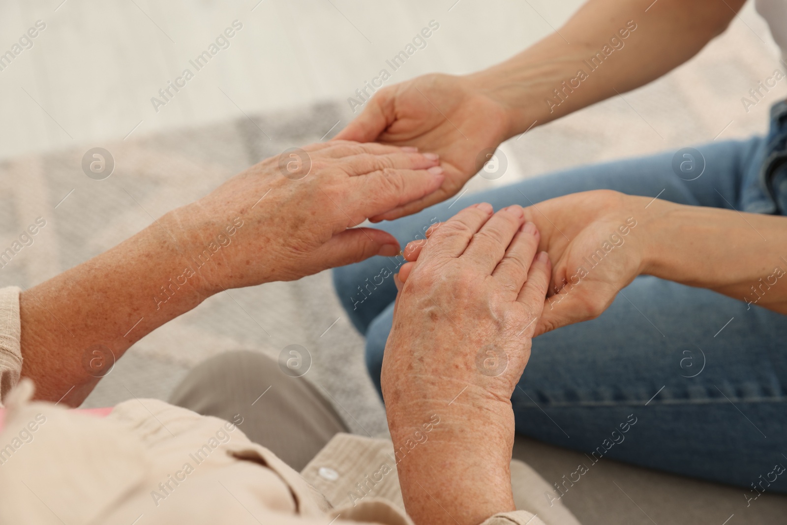 Photo of Caregiver supporting senior woman at home, closeup