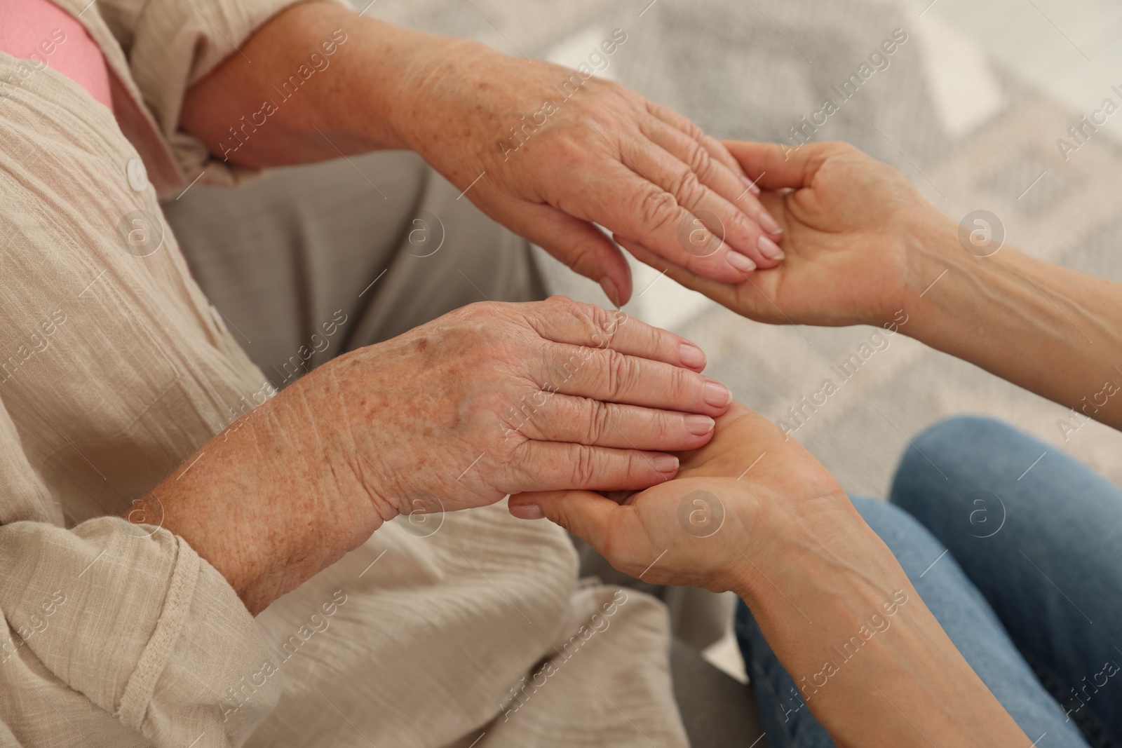 Photo of Caregiver supporting senior woman at home, closeup