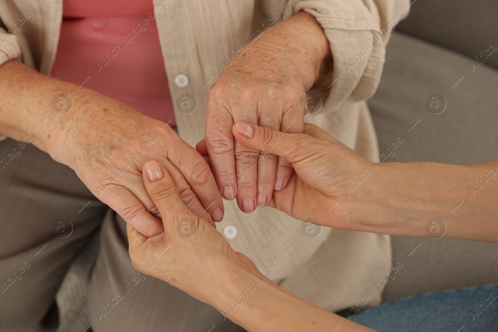 Photo of Caregiver supporting senior woman at home, closeup