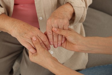 Caregiver supporting senior woman at home, closeup