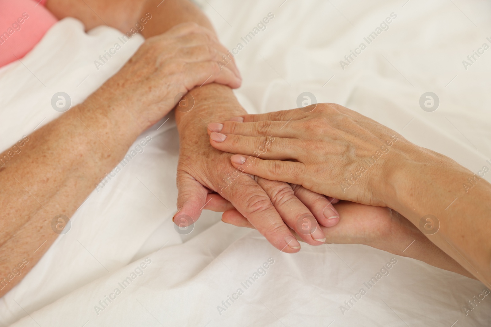 Photo of Caregiver supporting senior patient in bedroom at home, closeup