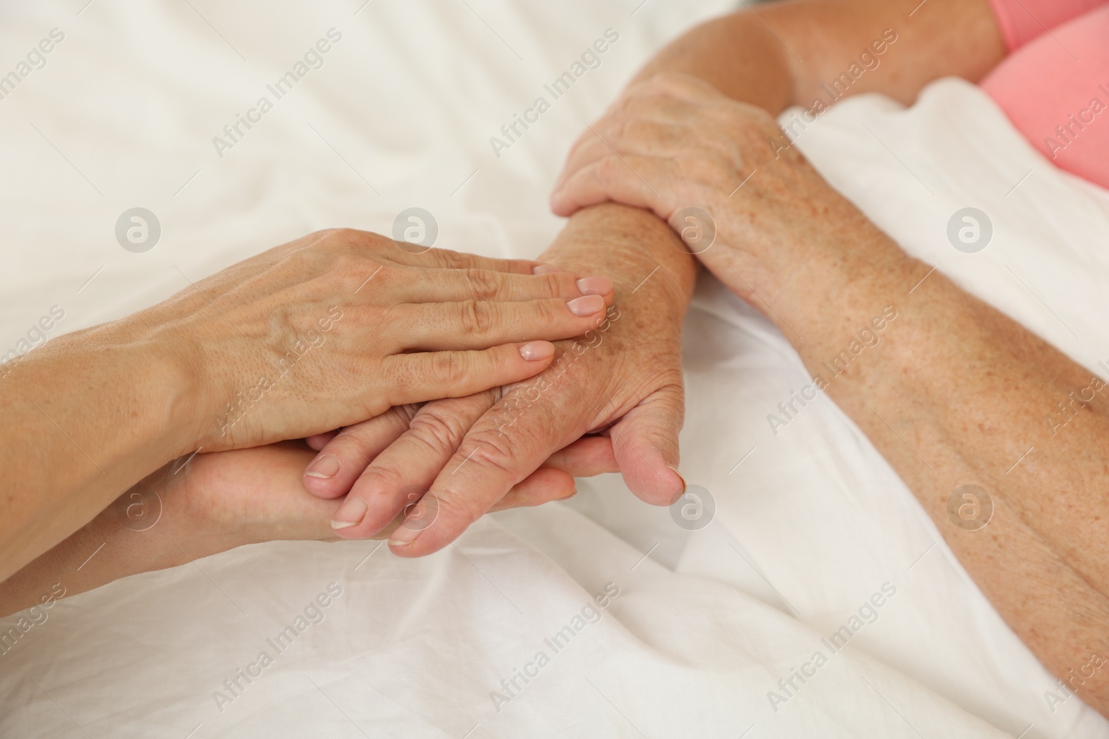 Photo of Caregiver supporting senior patient in bedroom at home, closeup