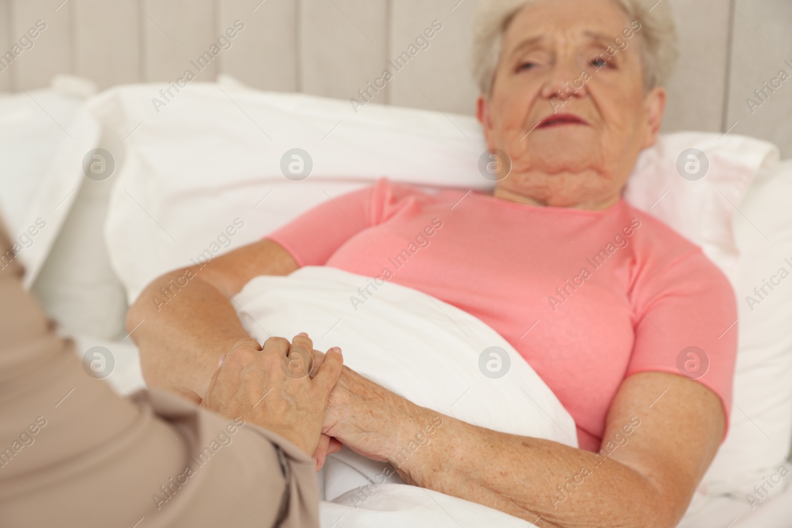 Photo of Caregiver supporting senior patient in bedroom at home, selective focus