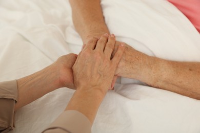 Photo of Caregiver supporting senior patient in bedroom at home, closeup