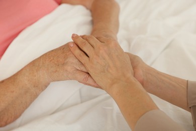 Caregiver supporting senior patient in bedroom at home, closeup