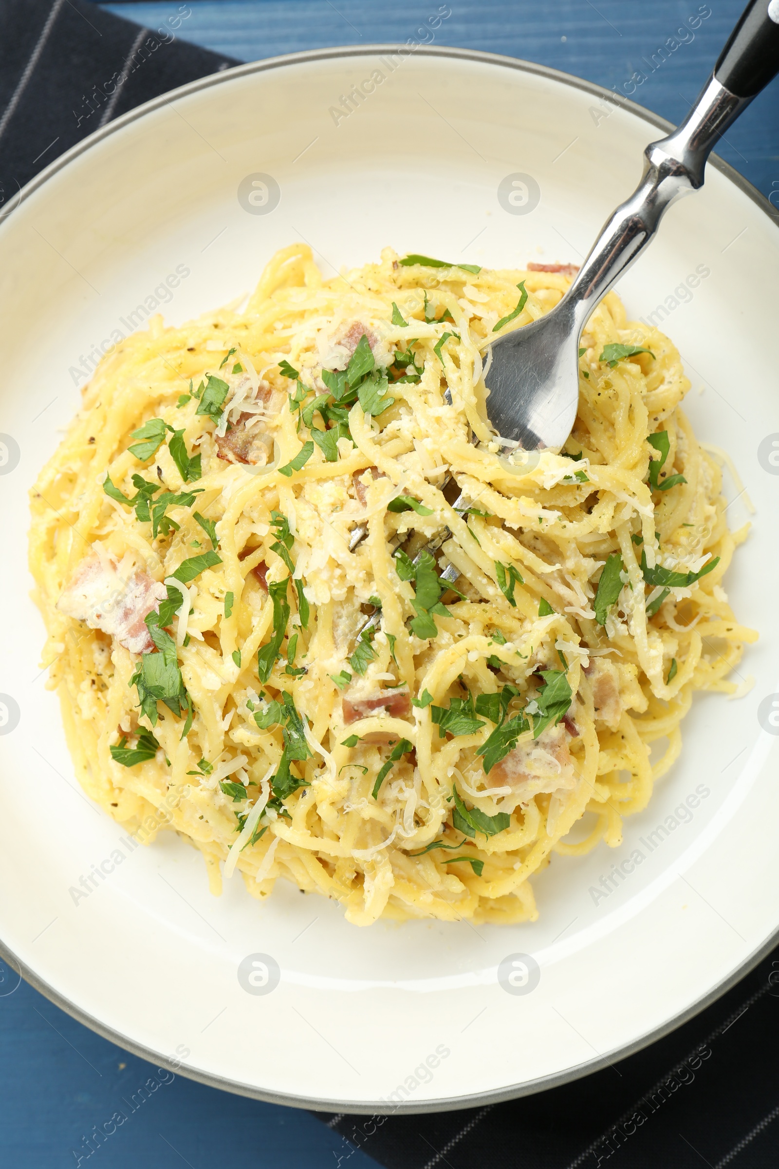 Photo of Delicious pasta Carbonara served on blue wooden table, top view