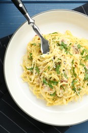 Photo of Delicious pasta Carbonara served on blue wooden table, top view