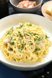 Photo of Delicious pasta Carbonara in bowl on table, closeup