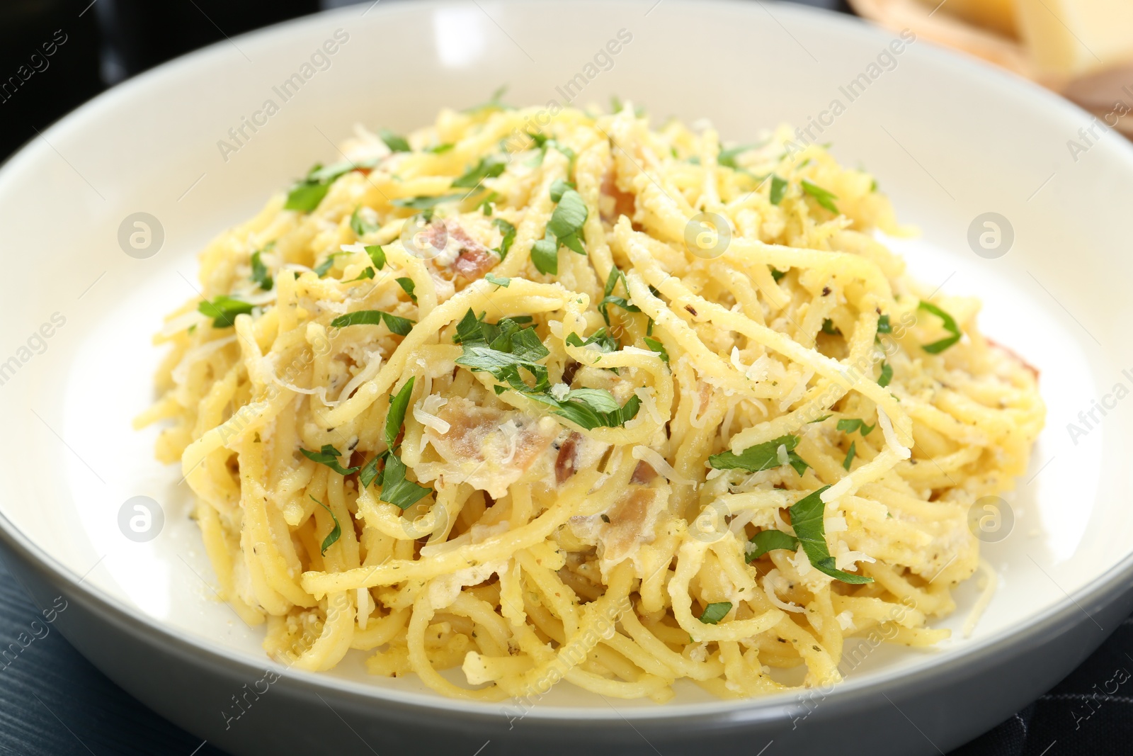 Photo of Delicious pasta Carbonara with ham and spices in bowl on table, closeup