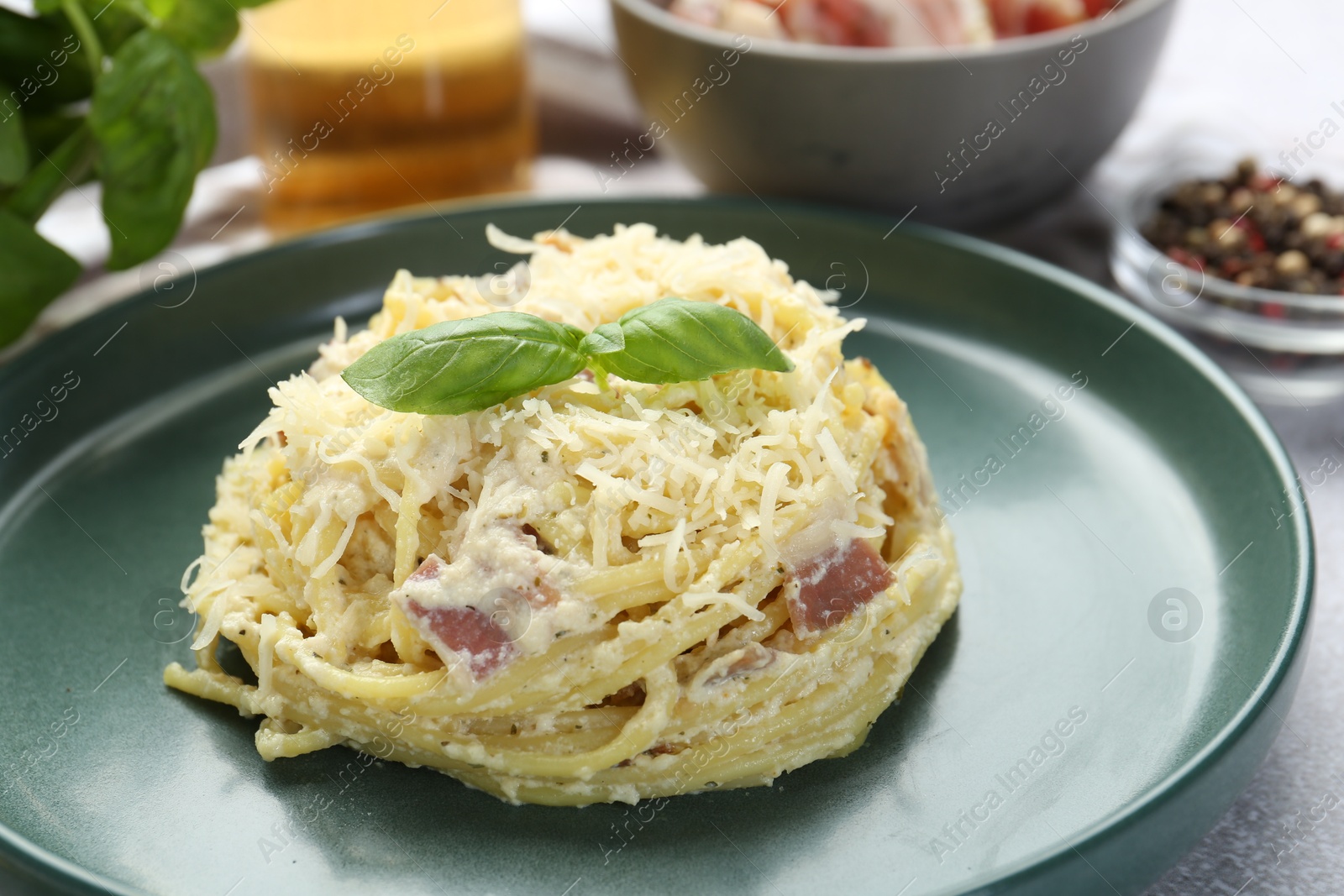 Photo of Delicious pasta Carbonara with basil on table, closeup