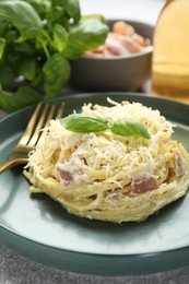 Photo of Delicious pasta Carbonara with basil on table, closeup