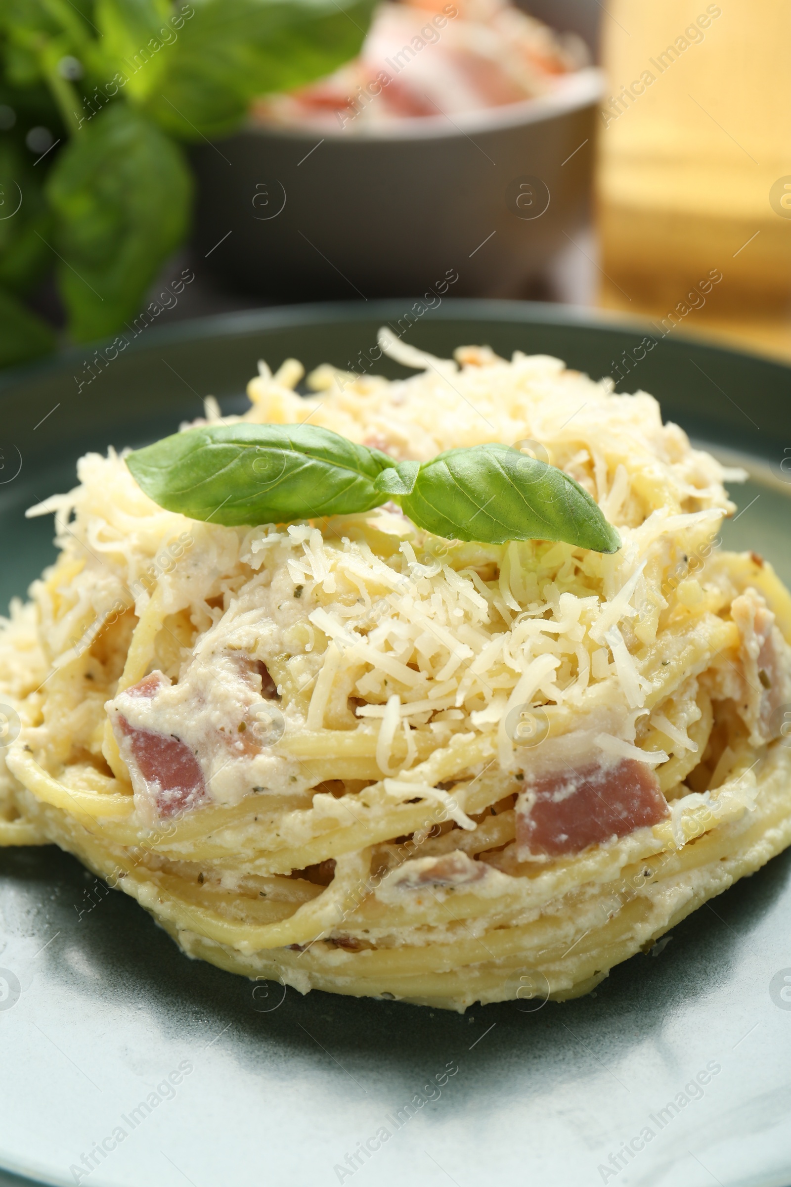 Photo of Delicious pasta Carbonara with basil on table, closeup