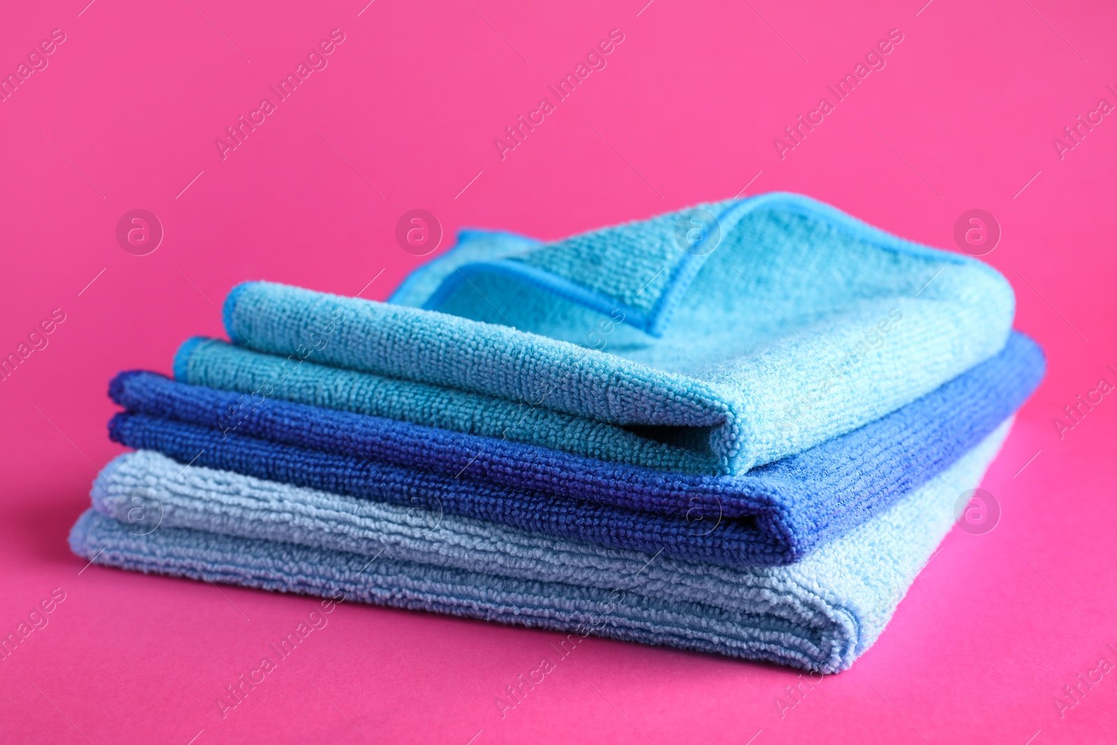 Photo of Stack of blue microfiber cloths on pink background