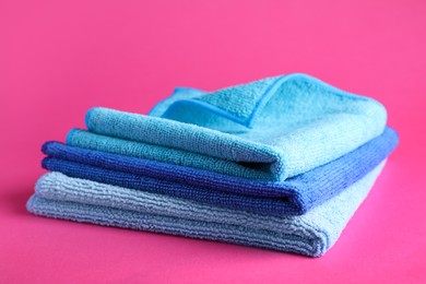 Photo of Stack of blue microfiber cloths on pink background