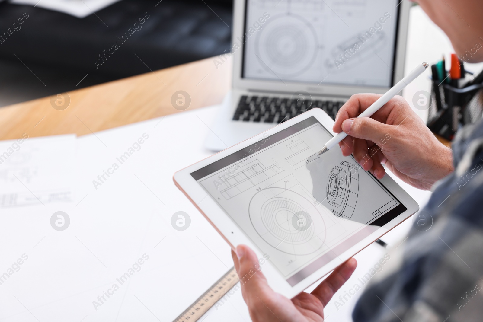 Photo of Architect making digital engineering drawing on tablet at table in office, closeup. Space for text