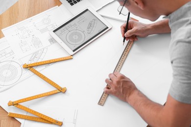 Architect making engineering drawing at wooden table in office, above view