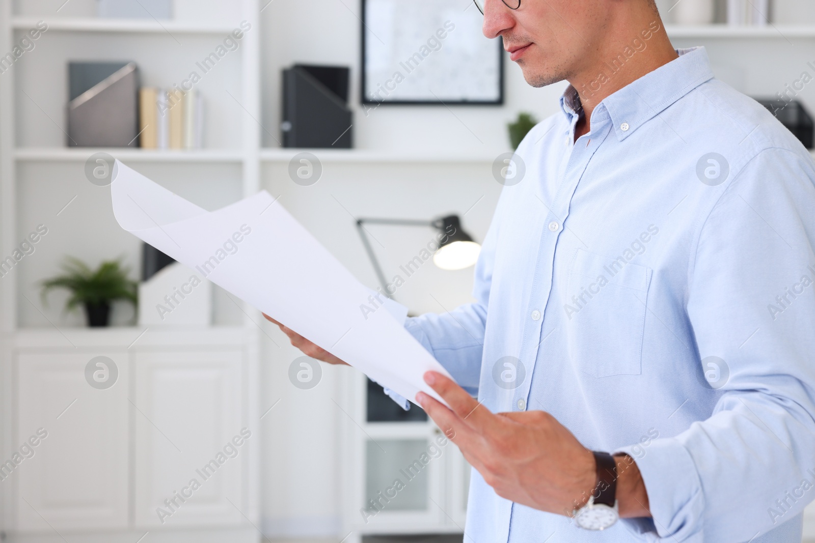 Photo of Architect holding paper sheet with engineering drawing in office, closeup