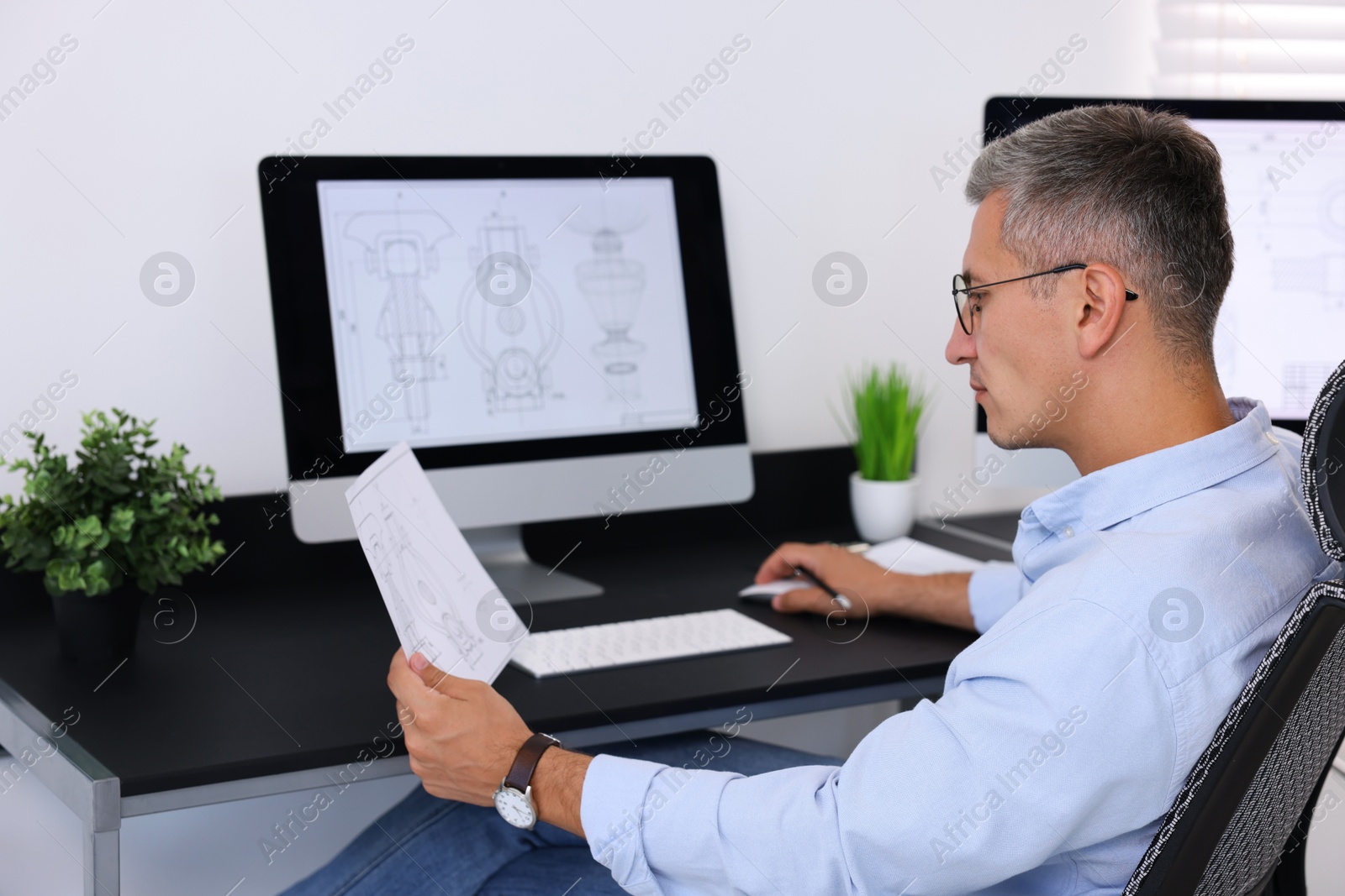 Photo of Architect checking engineering drawing at table in office