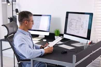 Architect checking engineering drawing at table in office