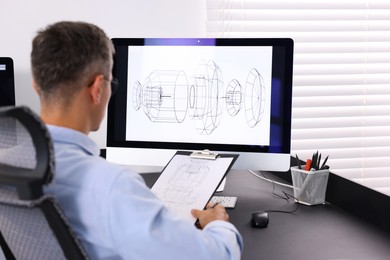 Photo of Architect checking engineering drawing at table in office