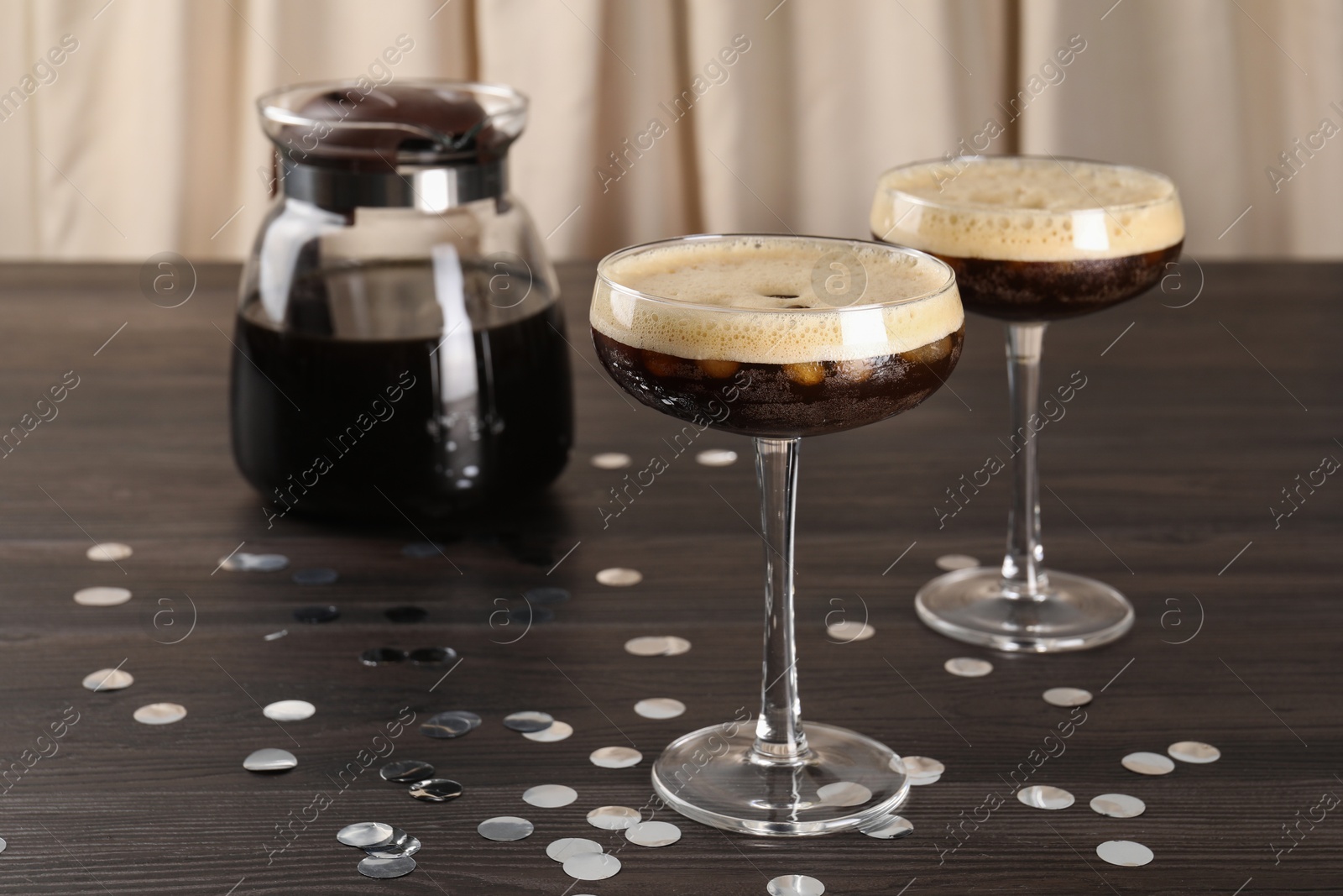 Photo of Fresh coffee cocktails in glasses, confetti and teapot on wooden table