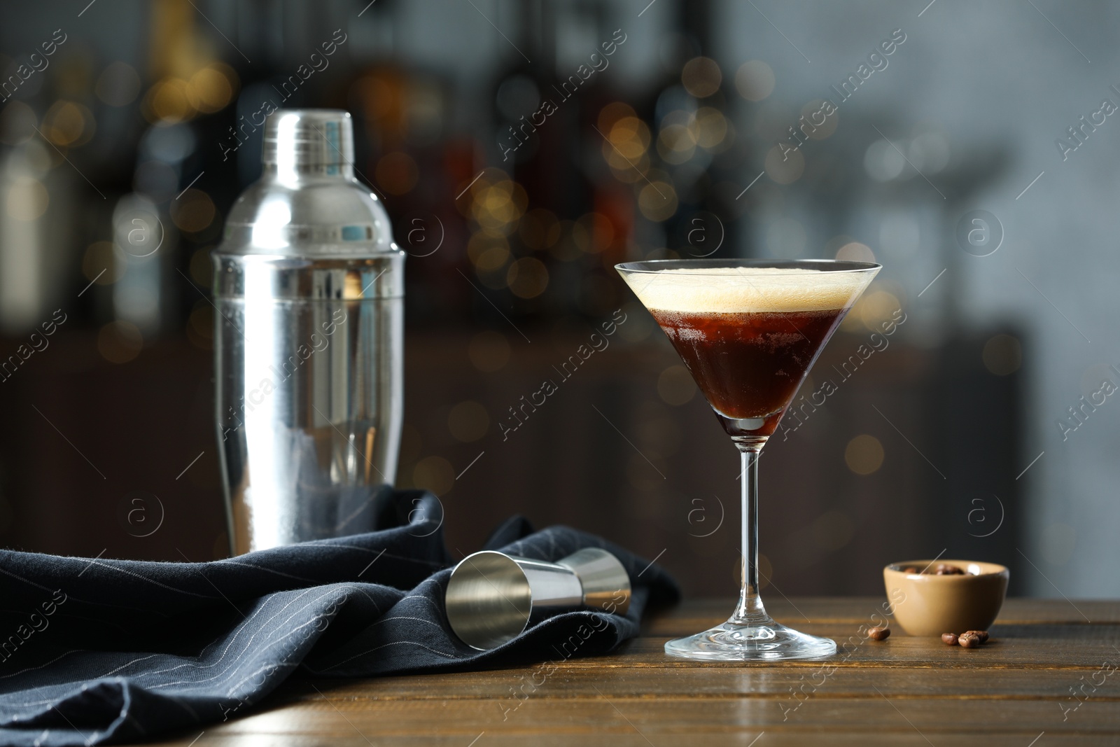 Photo of Refreshing cocktail, shaker, jigger and coffee beans on wooden table